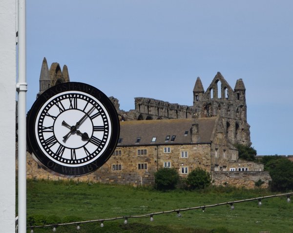 Public clock in Whitby with the 13th century ruins of the Abbey in background