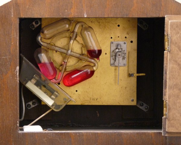 Table clock with “Weingeistaufzug” (“alcohol elevator”).  The black bar at the bottom-left is an electric heater - it heats the pink-coloured alcohol, causing it to rise to the upper vessel, which then drops under gravity, driving the mechanical clock movement.  Is there any form of energy not involved?!  Karl Jauch, Schwenningen c.1940 (Deutsches Uhrenmuseum Inv. 50-4135)